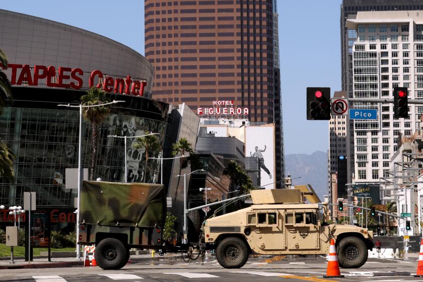 LOS ANGELES, CA - JUNE 7, 2020 - - A military vehicle crosses Figueroa Blvd. as members of the California National Guard leave the Convention Center after days of protest in downtown Los Angeles on June 7, 2020. (Genaro Molina/Los Angeles Times)