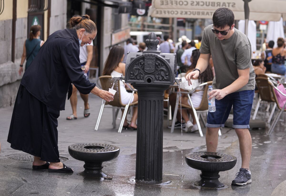 People drink from a public fountain in downtown Madrid, Spain, Sunday, June 12, 2022. Spain's weather service says a mass of hot air from north Africa is triggering the country's first major heat wave of the year with temperatures expected to rise to 43 degrees Celsius (109 degrees Fahrenheit) in certain areas. (AP Photo/Paul White)