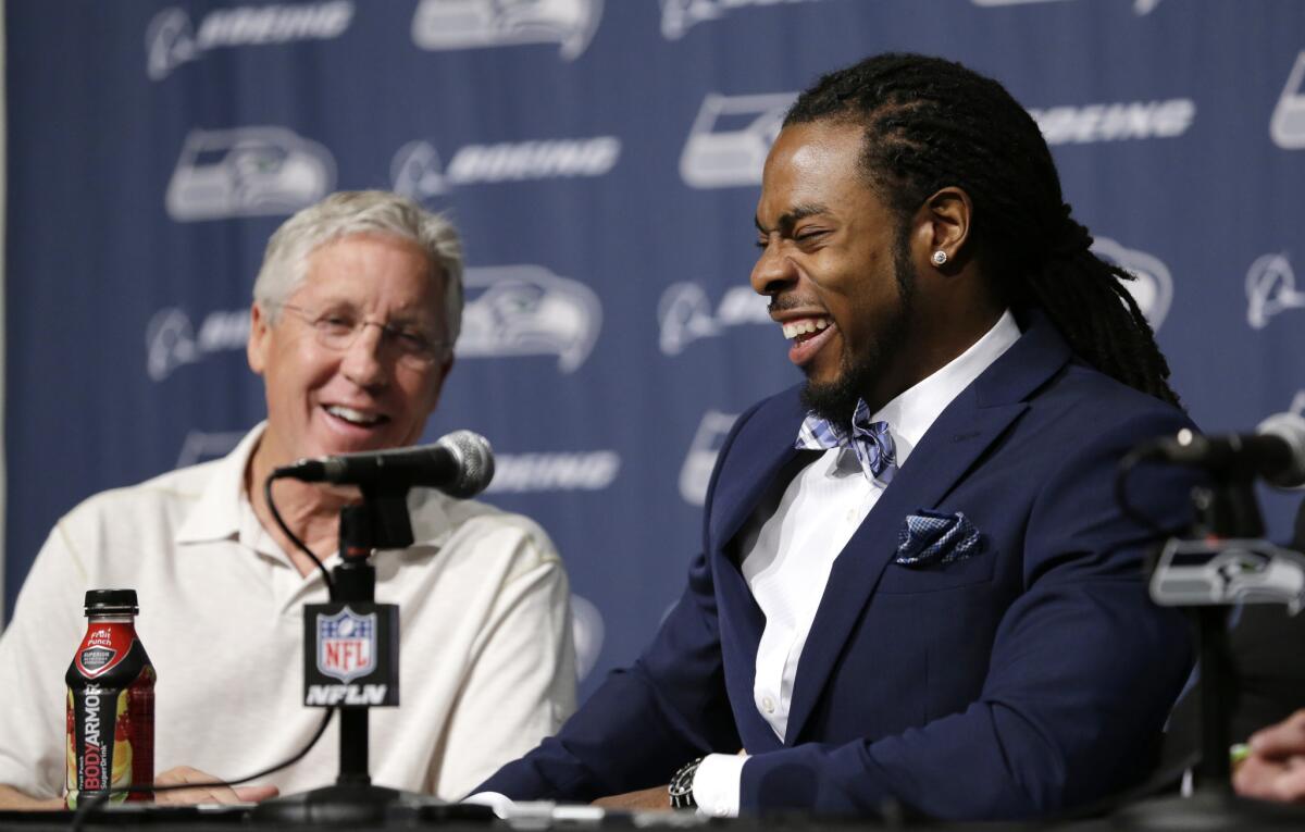 Seahawks cornerback Richard Sherman shares a laugh with the media and Coach Pete Carroll during a news conference last week to announced he's signed a four-year contract extension.