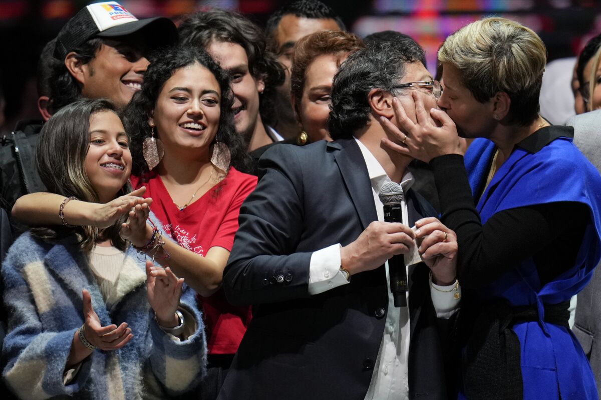 Veronica Alcocer kisses her husband, President elect Gustavo Petro, under the look of their daughters Antonella, left, and Sofia as they celebrate before supporters after he won a runoff presidential election in Bogota, Colombia, Sunday, June 19, 2022. (AP Photo/Fernando Vergara)