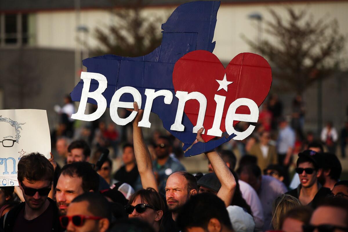 People cheer as Democratic presidential candidate Bernie Sanders walks on stage at a campaign rally in Queens, N.Y., on Monday.