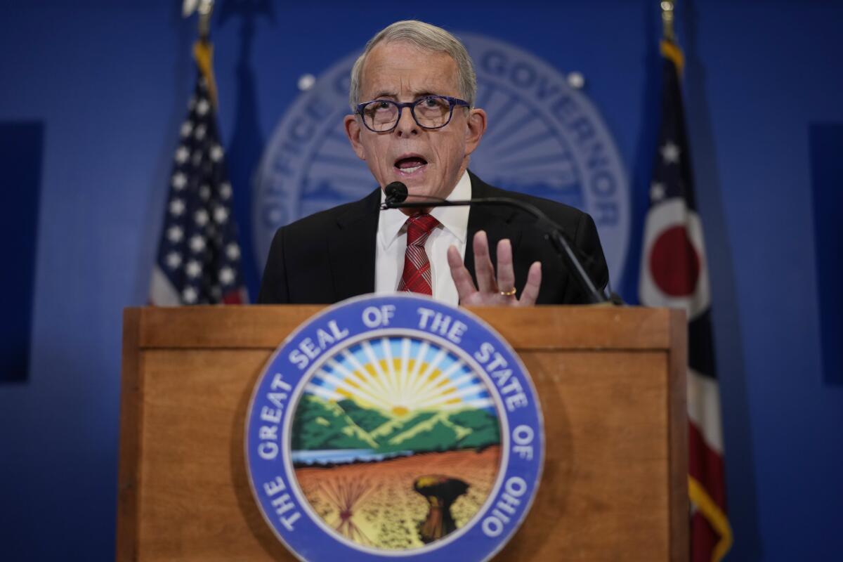 Ohio Gov. Mike DeWine speaks at a lectern in front of two flags.