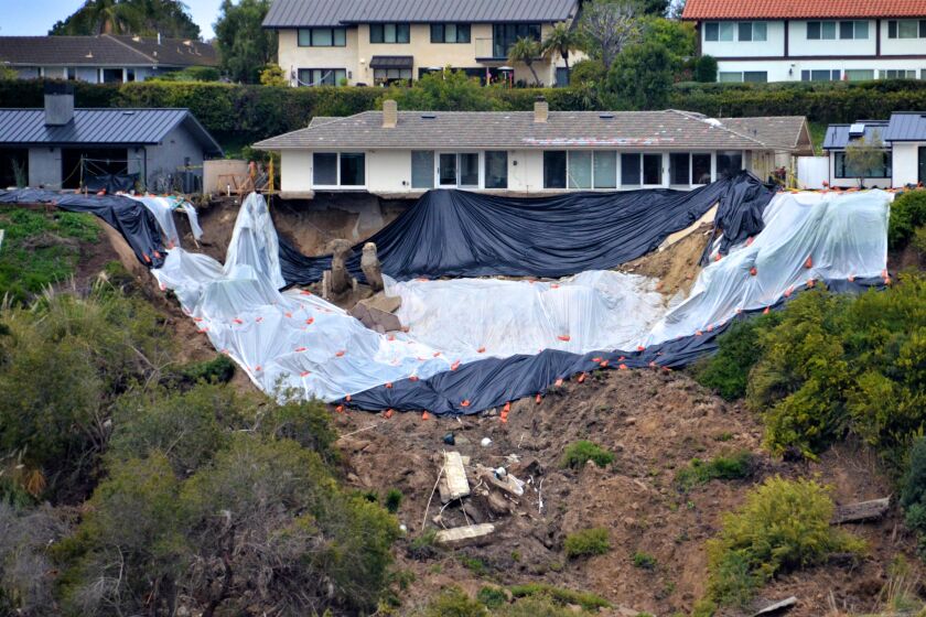 The hillside behind a home at 1930 Galaxy Drive in Newport Beach were covered Sunday in anticipation of further rain damage. 