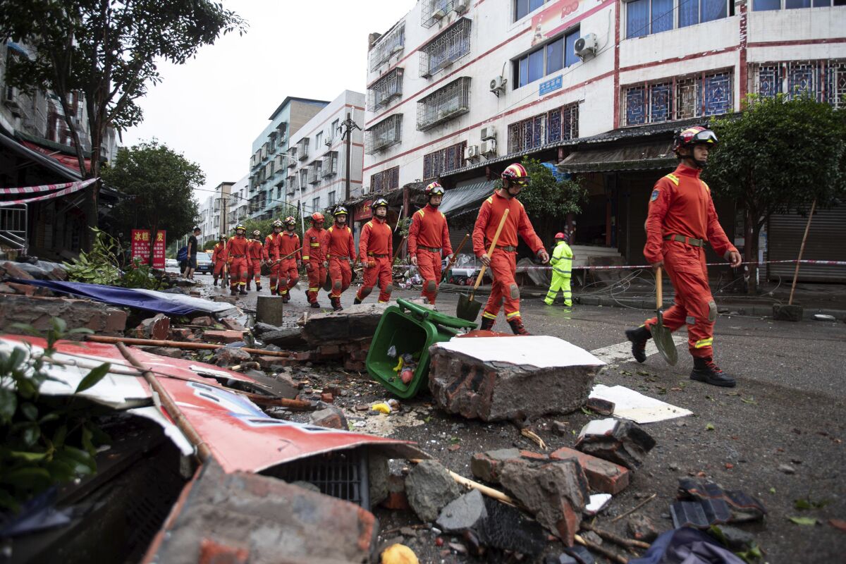 In this photo released by Xinhua News Agency, rescue workers walk near debris in the aftermath of an earthquake in Fuji Township of Luxian County in southwestern China's Sichuan Province, on Thursday, Sept. 16, 2021.An earthquake collapsed homes, killed some and injured others Thursday in southwest China's Sichuan province, state media reported. (Jiang Hongjing/Xinhua via AP)