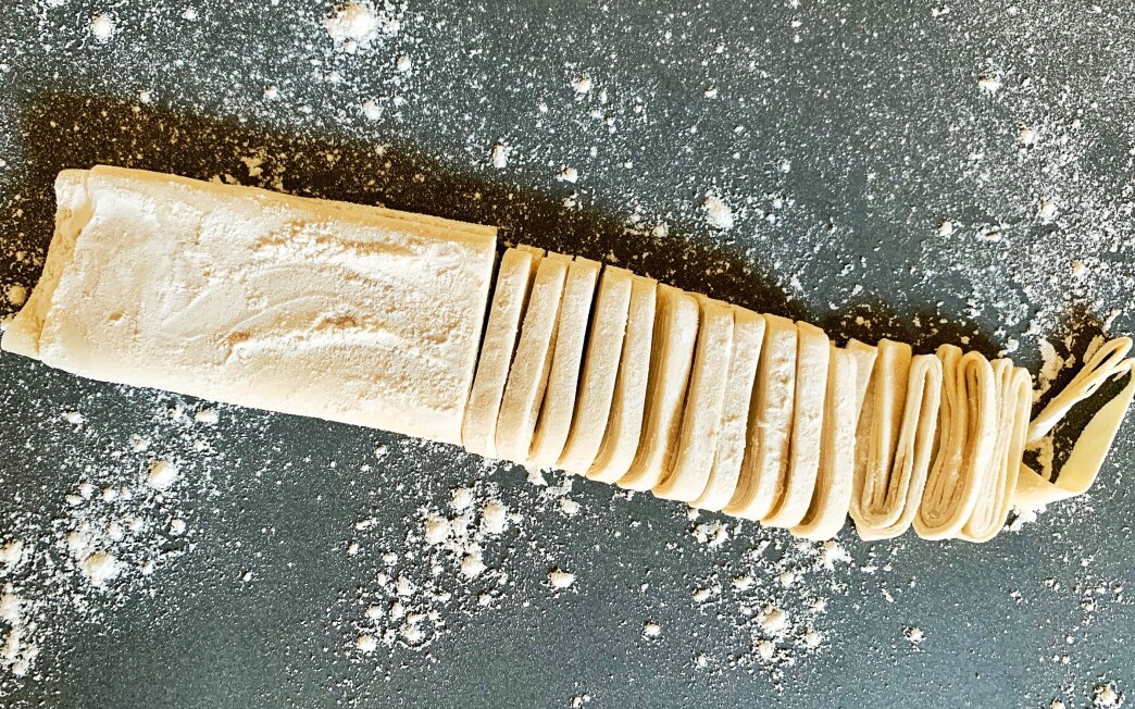A roll of handmade noodle dough, partially sliced into noodles