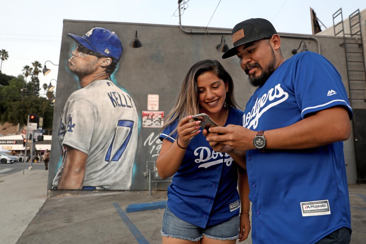 Marco Torres and Cinthya Ferrel of Los Angeles admire a photo in front of a mural of Joe Kelly making a pouty face