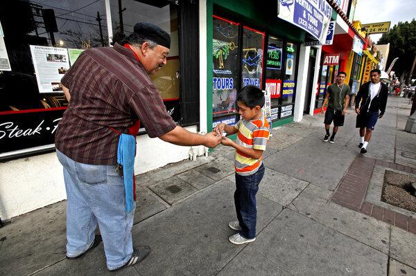 Gogo's Bistro's baker Roderick Sweetwine Sr., left, 55, hands out free samples of barbecue to Devon Urbina, 8, of Boyle Heights.