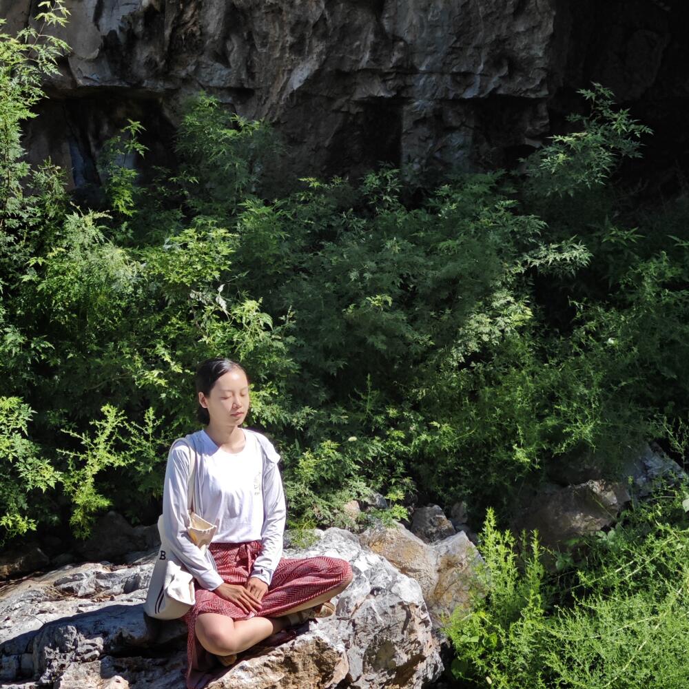 A young person meditates outdoors.