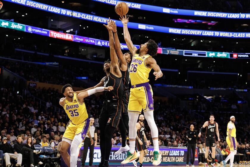 LOS ANGELES, CA - FEBRUARY 13, 2024: Los Angeles Lakers guard Spencer Dinwiddie (26) gets his finger tips on a rebound against Detroit Pistons center James Wiseman (13) and Pistons forward Troy Brown Jr. in the first half at Crypto.com Arena on February 13, 2024 in Los Angeles, California.(Gina Ferazzi / Los Angeles Times)