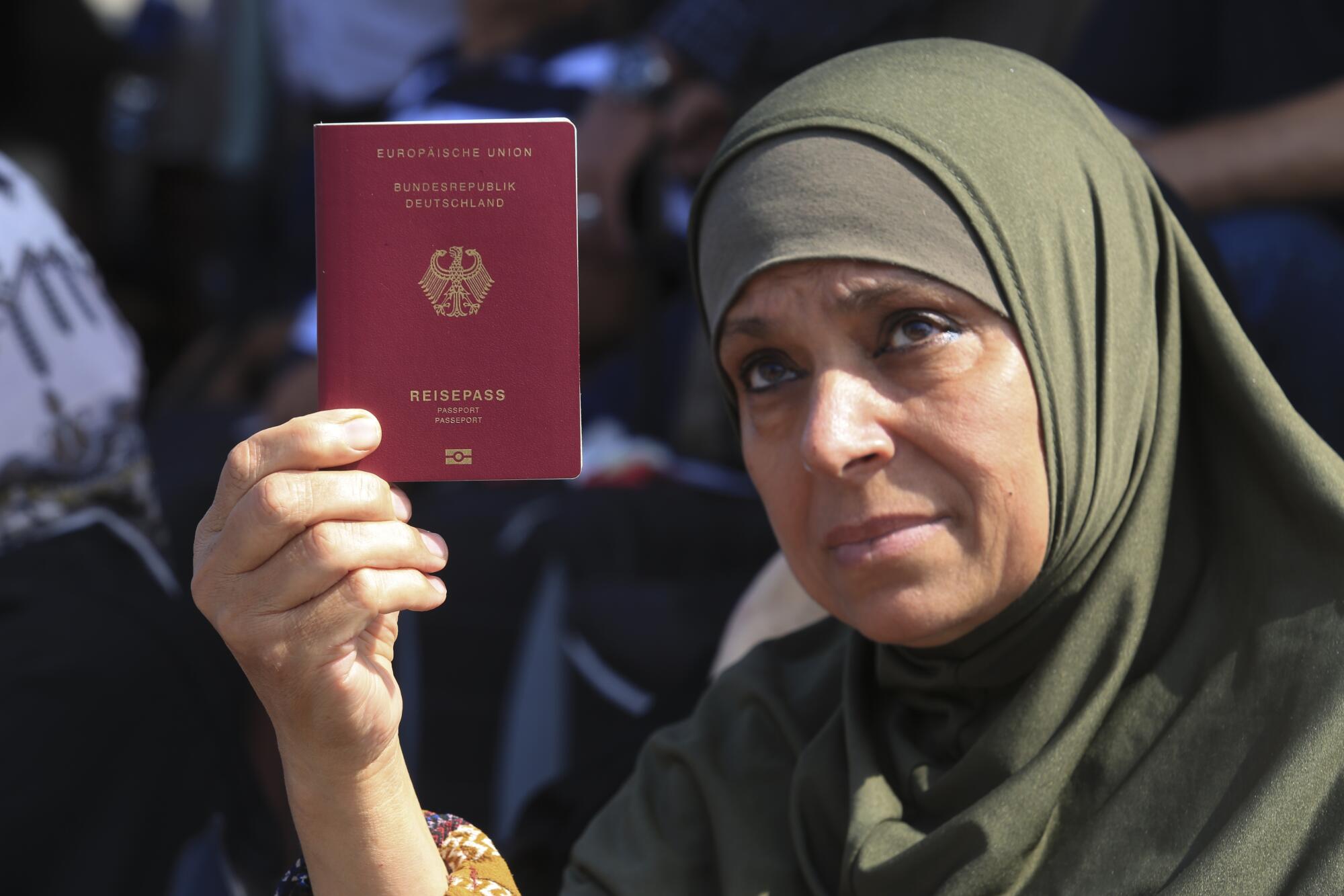 Palestinian woman holding up her German passport at Rafah border crossing into Egypt