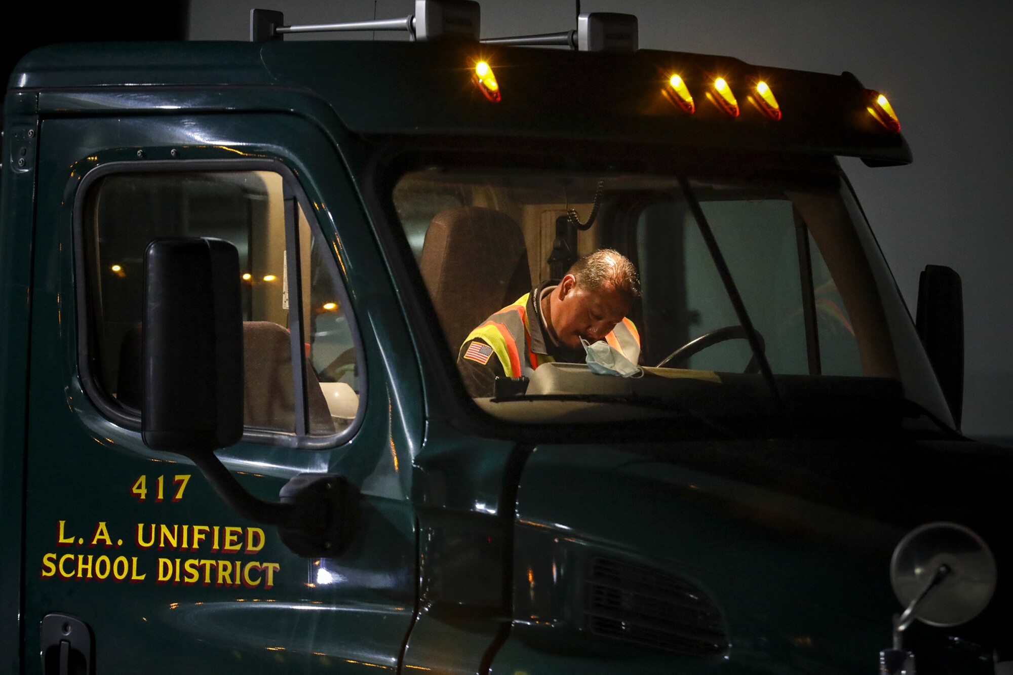 In the early morning darkness a truck driver goes over paperwork before going out delivering food from LAUSD Procurement Services Center in Pico Rivera.