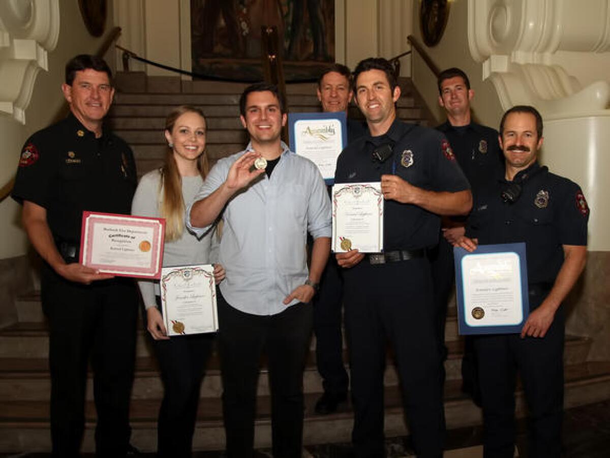 Members of the Burbank Fire Department, along with City Council members, honored Konrad Lightner and his wife, Jennifer, after they saved the life of a 3-year-old boy who fell from a third-story window.