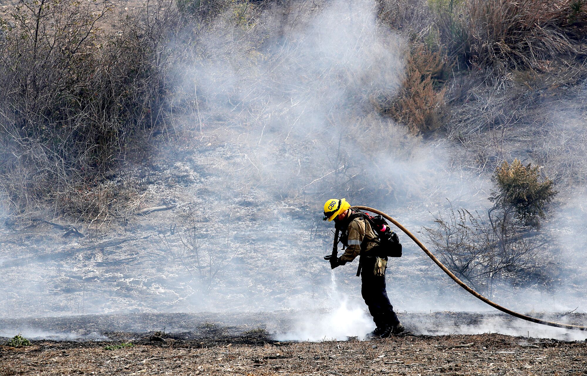 A firefighter puts out hot spots in the burn zone of the Alisal fire near Goleta on Wednesday.