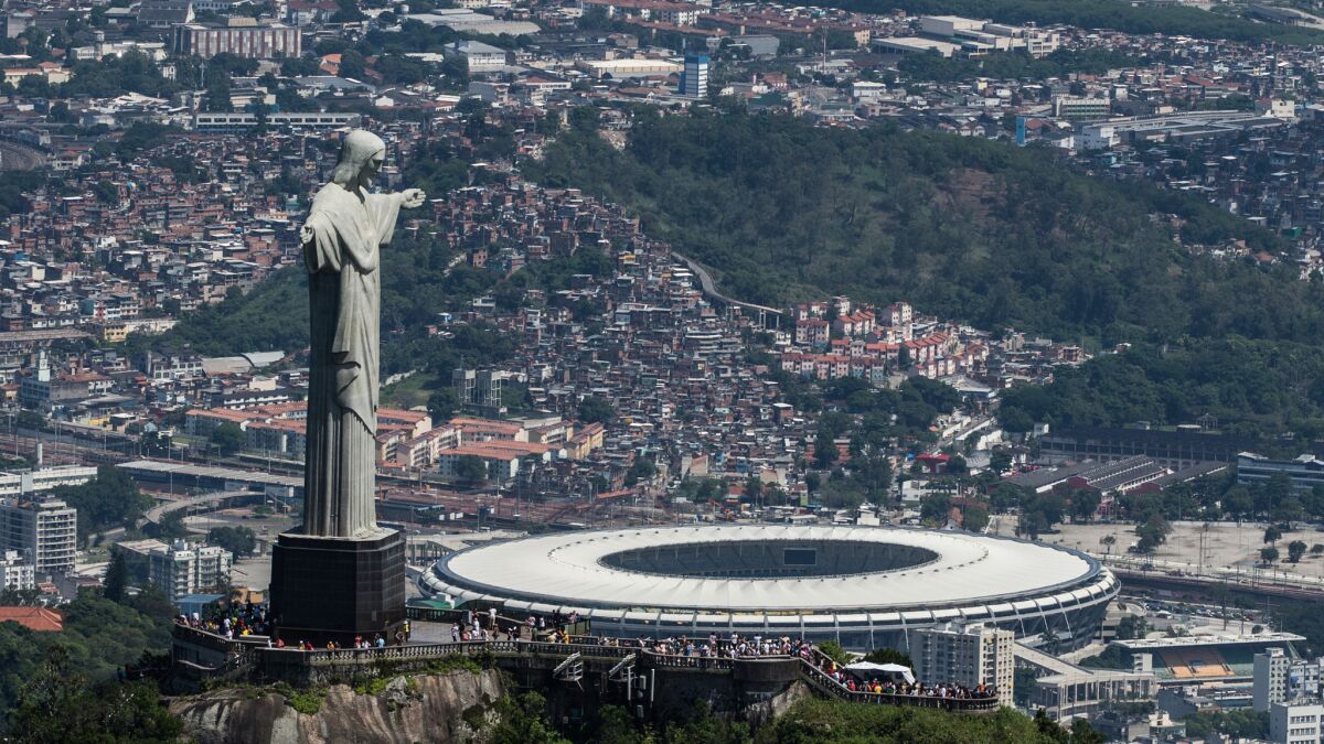 An aerial view of Mario Filho stadium looms beyond the Christ the Redeemer statue atop Corcovado Hill in Rio de Janeiro. The stadium, also known as Maracana stadium, will host the World Cup final and the 2016 Summer Olympics.