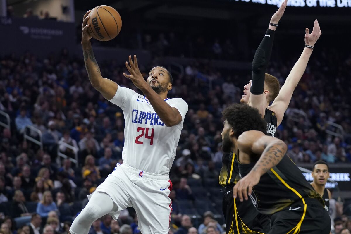 Clippers forward Norman Powell shoots at Golden State Warriors forward Anthony Lamb and guard Donte DiVincenzo.