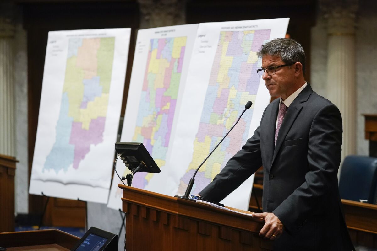 Indiana Senate President Pro Tem Rodric Bray speaks at a lectern near redistricting maps.  