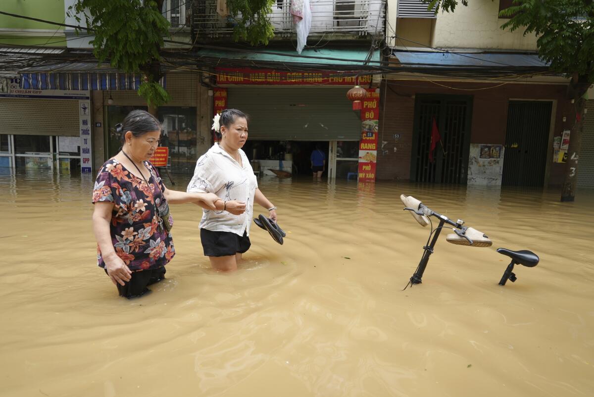 People wade in a flooded street in Hanoi.