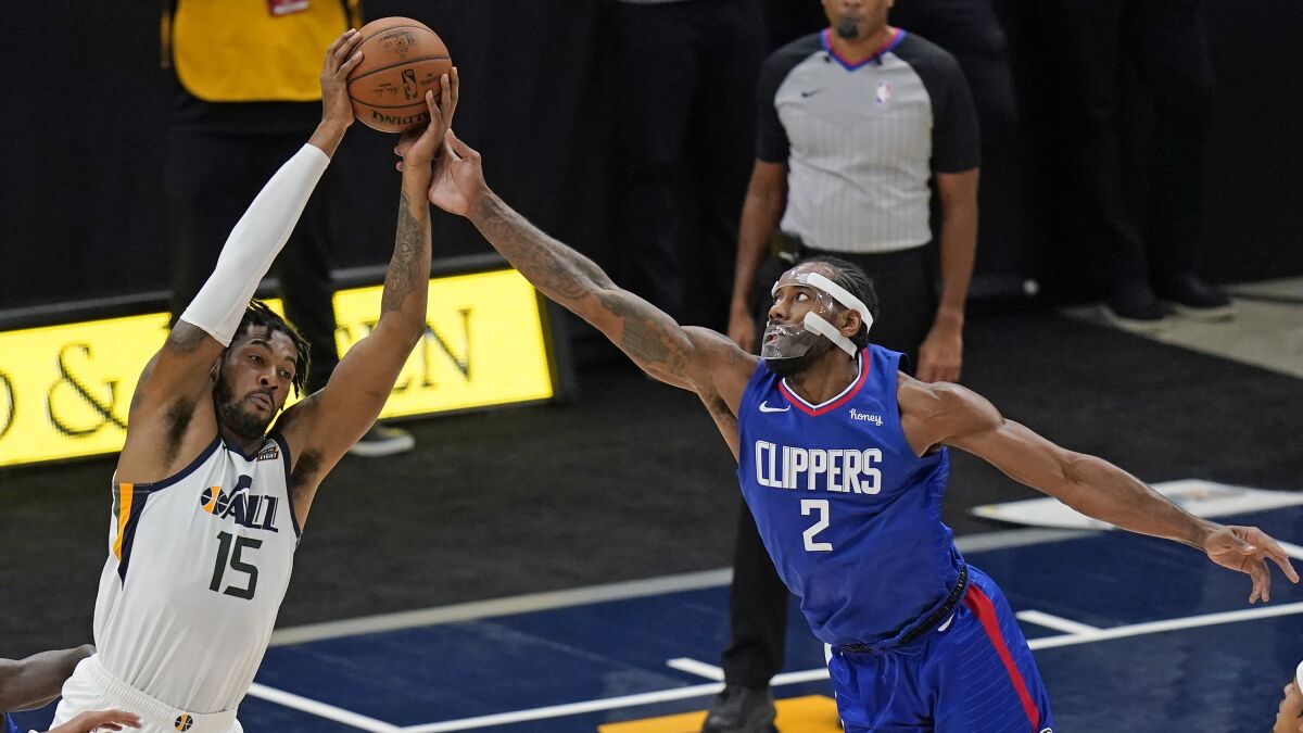 Utah Jazz center Derrick Favors and Clippers forward Kawhi Leonard reach for a rebound.