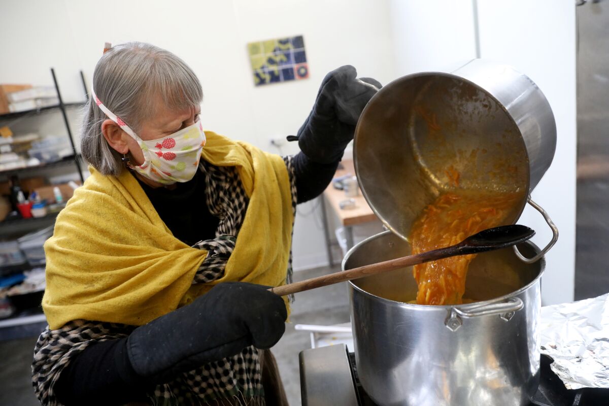 A masked June Taylor pours clementine marmalade from one pot into another.