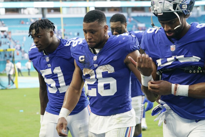 New York Giants outside linebacker Azeez Ojulari (51), running back Saquon Barkley (26) and wide receiver Darius Slayton (86) walk off the field at the end of an NFL football game, Sunday, Dec. 5, 2021, in Miami Gardens, Fla. The Dolphins defeated the Giants 20-9. (AP Photo/Lynne Sladky)