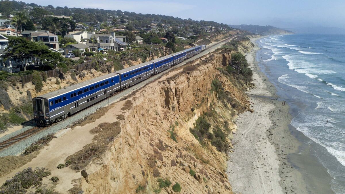 An Amtrak Surfliner train travels along the eroding sandstone cliffs in Del Mar. 