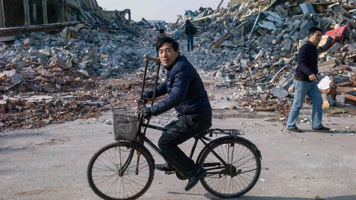 A man on a bicycle passes a block of demolished buildings in Beijing on Nov. 27, 2017.