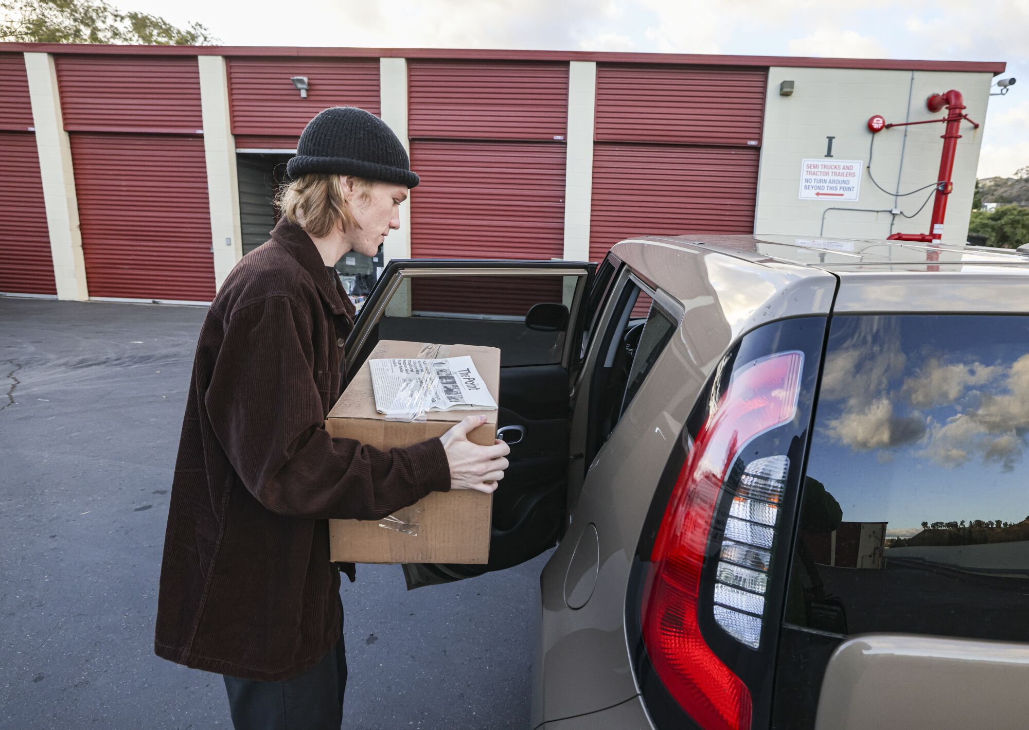 Zach Dinsmore, staff writer at The Point weekly, picks up a box of his school paper at Price Self Storage.