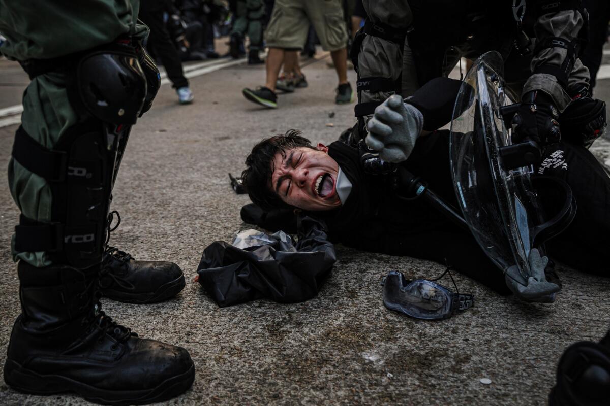 Police officers in riot gear pin down young female demonstrators near the HK Police Headquarters during the protest in Hong Kong. 