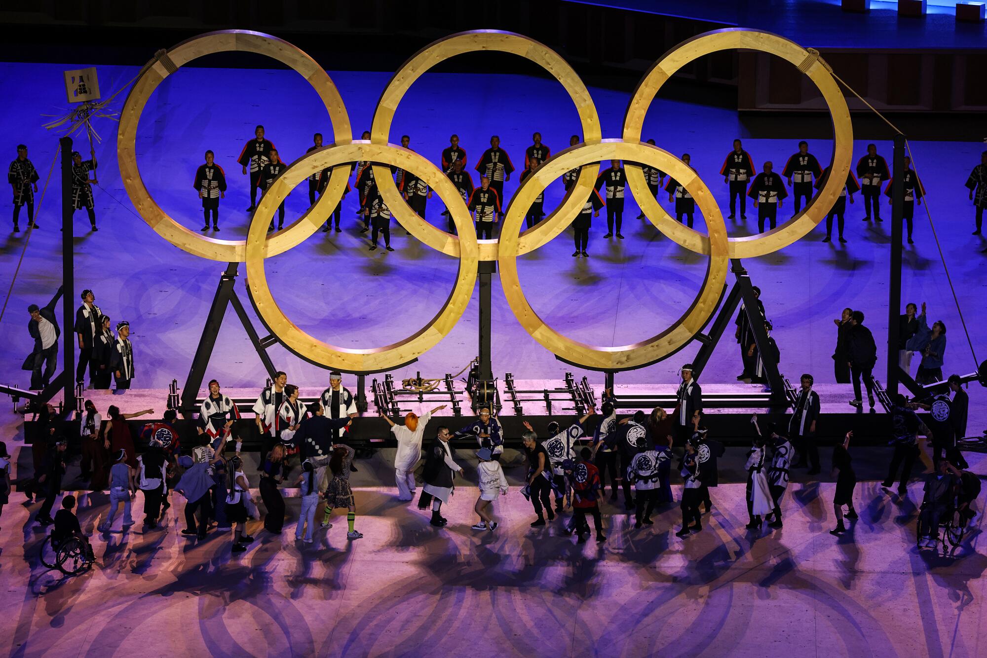 Performers surround the Olympic rings on stage