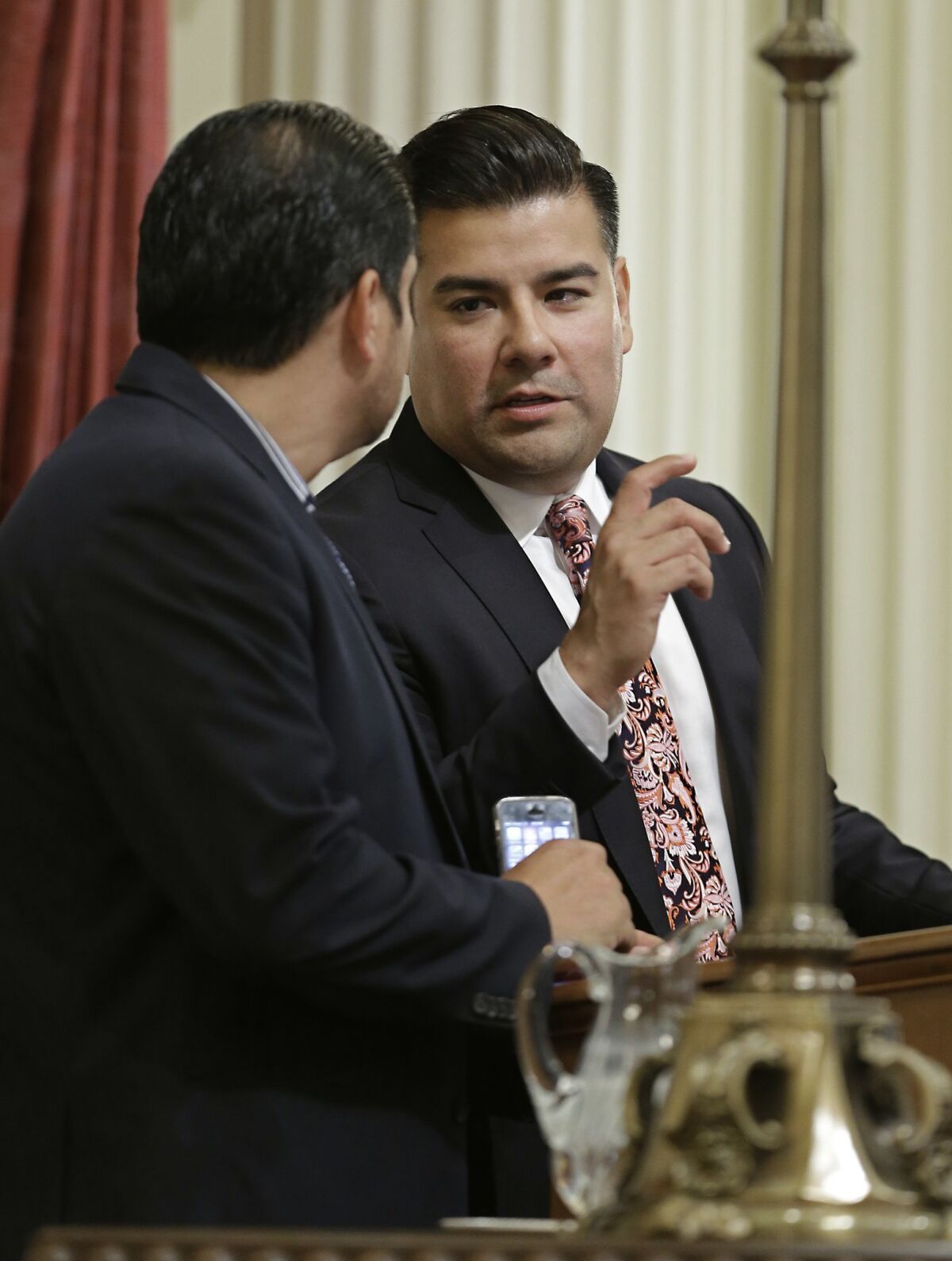 State Sen. Ricardo Lara, D-Bell Gardens, right, talks with Sen. Ben Hueso, D- San Diego, during the Senate session in Sacramento, Calif., Thursday, May 28, 2015. By a 28-11 vote the Senate approved Lara's bill, SB482, that will require California doctors to a check a statewide database before prescribing narcotics and sent it to the Assembly. (AP Photo/Rich Pedroncelli)
