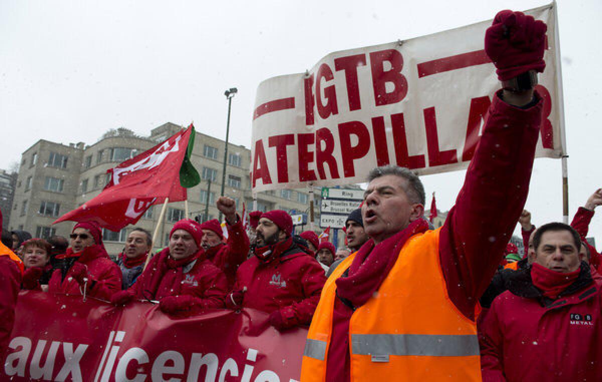 Union members march in solidarity for Caterpillar employees who have lost their jobs outside of a European Union summit in Brussels aimed at boosting growth and reducing unemployment.