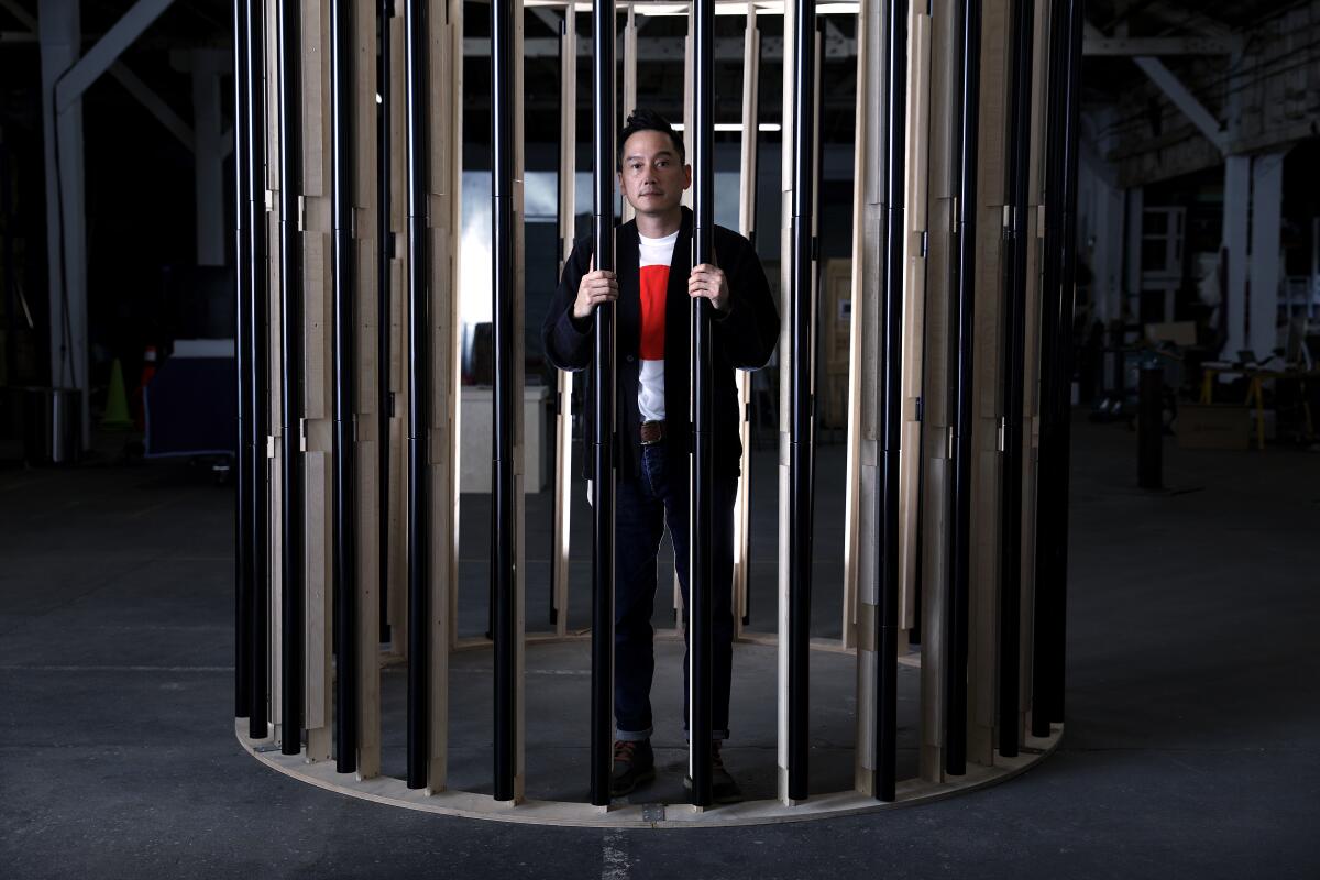 Glenn Kaino stands inside a rounded, columned sculpture in his studio