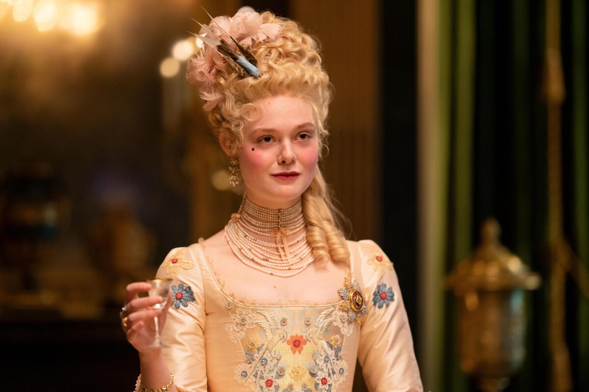 Catherine the Great, portrayed by Elle Fanning, holds up a glass.