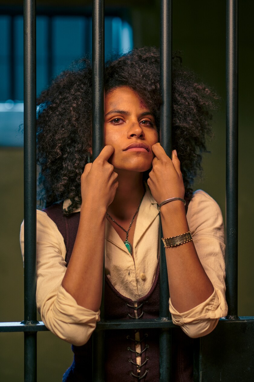 A woman stands behind the bars of a cell