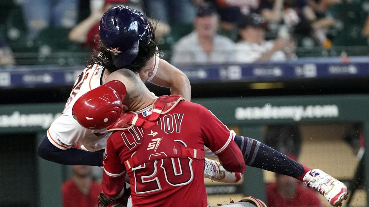 Houston Astros baserunner Jake Marisnick collides with Angels catcher Jonathan Lucroy while trying to score during the eighth inning of the Angels' 11-10 loss Sunday.