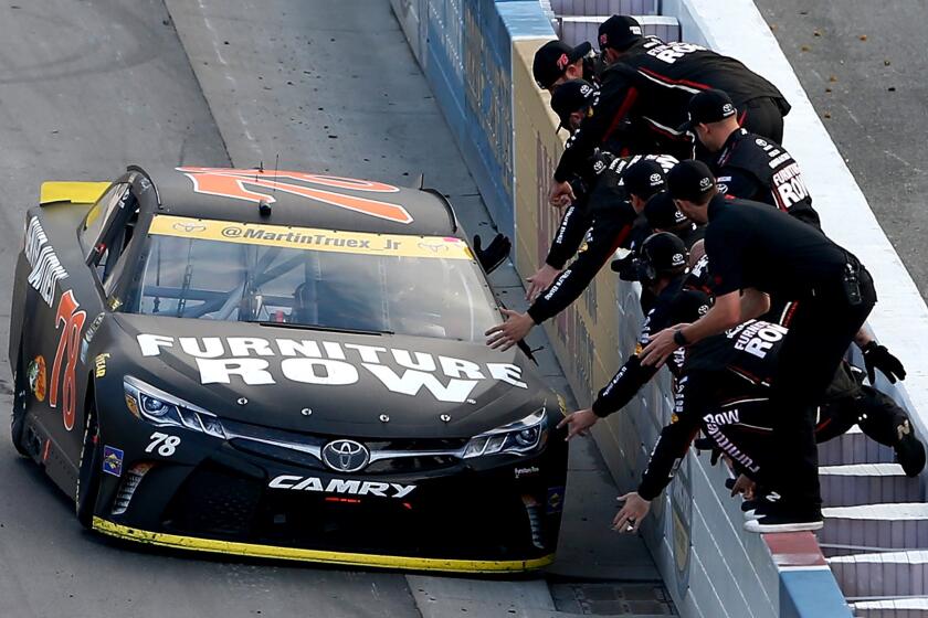 Martin Truex Jr. drives his car along the retaining wall to receive congratulations from team members after winning the Sprint Cup race on Sunday.