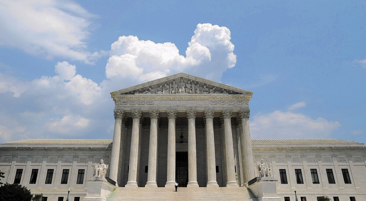 The U.S. Supreme Court building against a blue sky and clouds.
