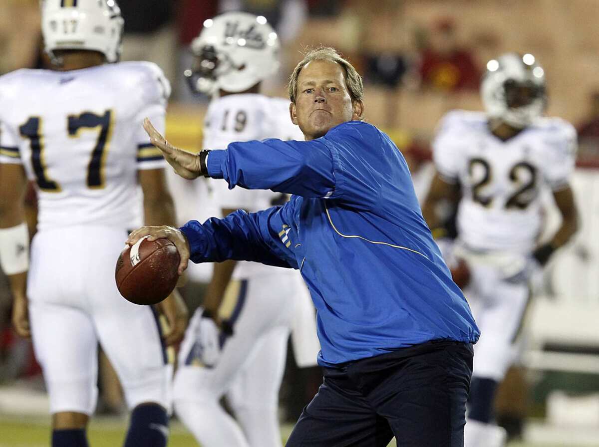 UCLA coach Rick Neuheisel, a former Bruins quarterback, throws a pass as his players warm up in 2011.