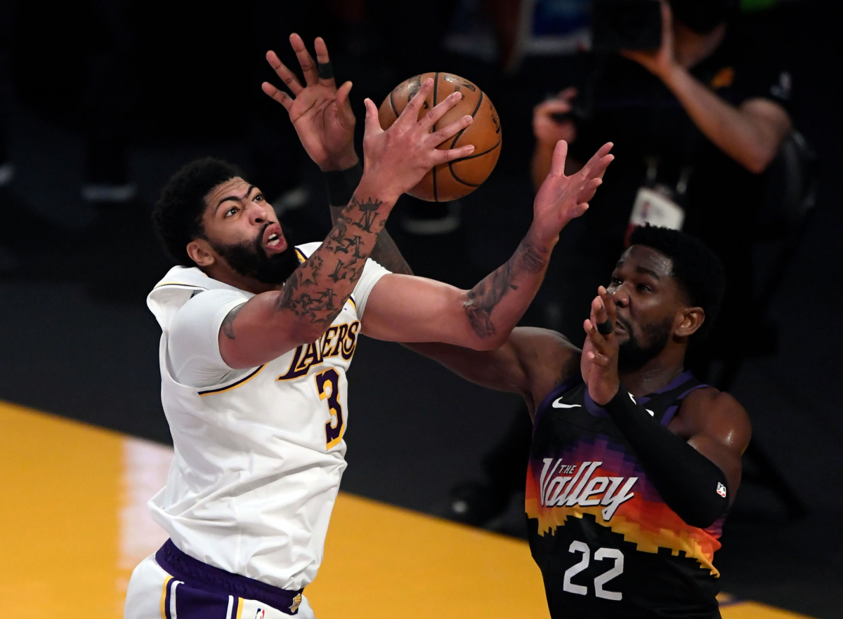 Anthony Davis #3 of the Los Angeles Lakers pulls down a defensive rebound against Suns center Deandre Ayton.