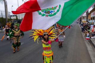 East Los Angeles, CA - September 15: Crystal Ayon, 14, of Whittier, waves a large Mexican flag during the East L.A. Mexican Independence Day Parade along East Cesar E. Chavez Avenue on Sunday, Sept. 15, 2024 in East Los Angeles, CA. (Brian van der Brug / Los Angeles Times)