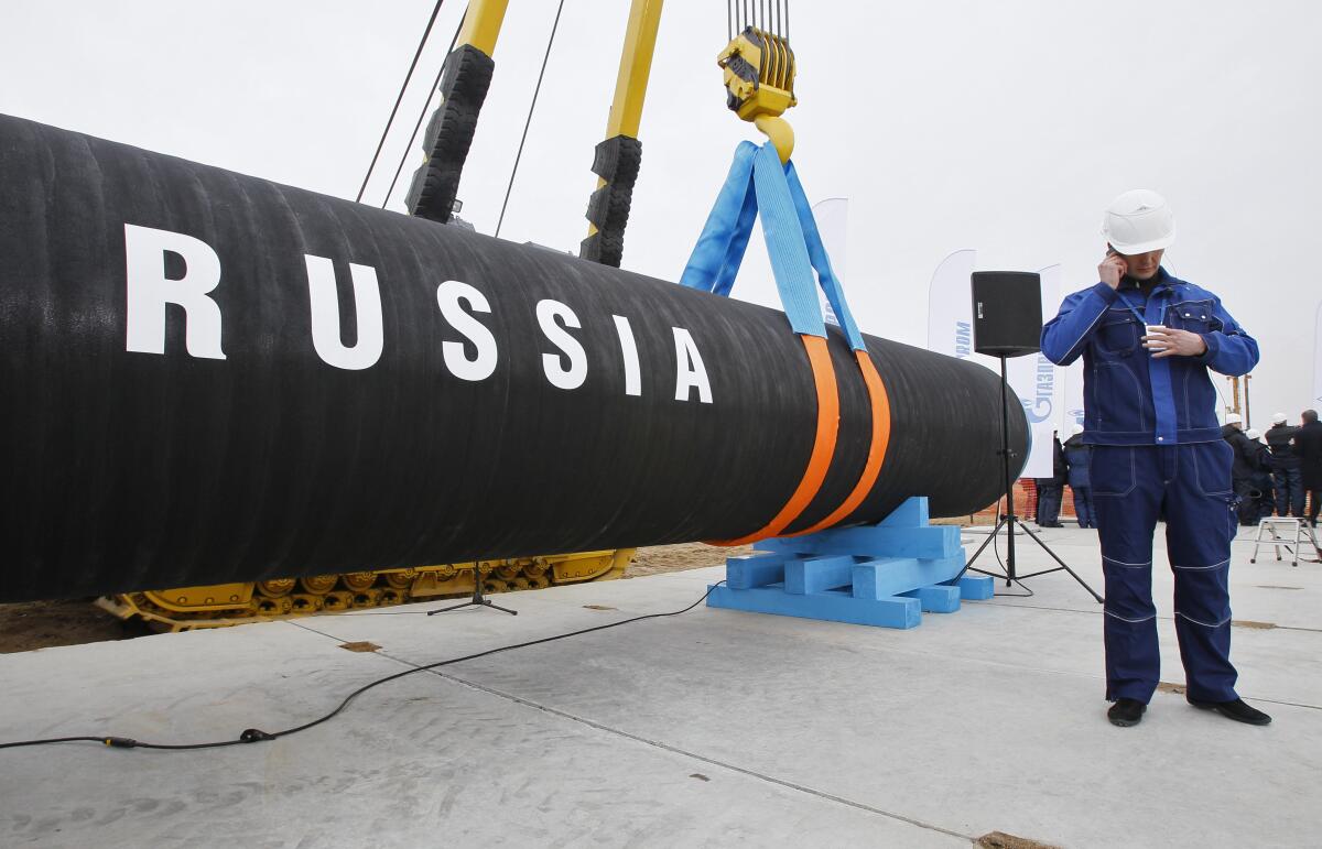 A construction worker next to a pipeline section labeled "RUSSIA"