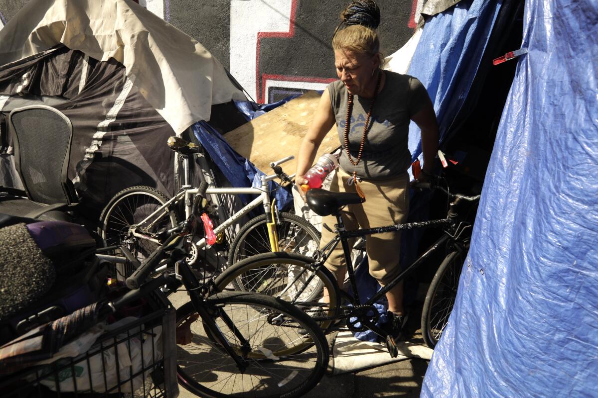 A woman with a few old bikes outside a blue tarp tent
