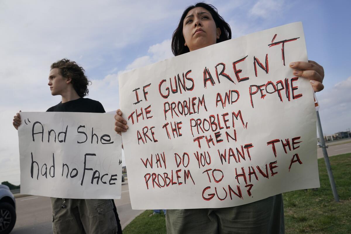 Two protesters hold signs calling out gun violence 