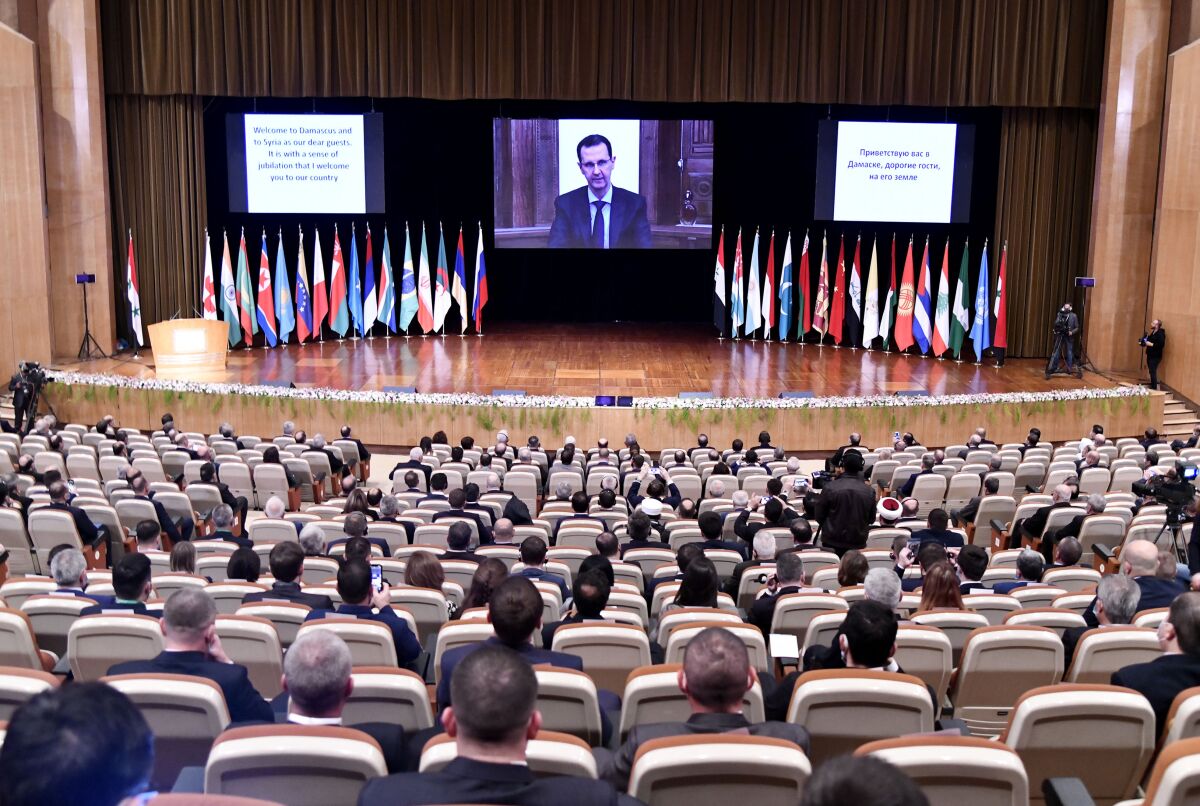 CORRECTS DATE TO NOV. 11, 2020 -- This photo released by the Syrian official news agency SANA, shows Syrian President Bashar Assad virtually addressing the opening session of a two-day international conference on the return of refugees to Syria, organized by Russia, in Damascus, Syria, Wednesday, Nov. 11, 2020. The Syrian government is working to secure the return of millions of refugees who fled war in their country, but Western sanctions are hindering the work of state institutions, complicating those plans, Assad said Wednesday. (SANA via AP)