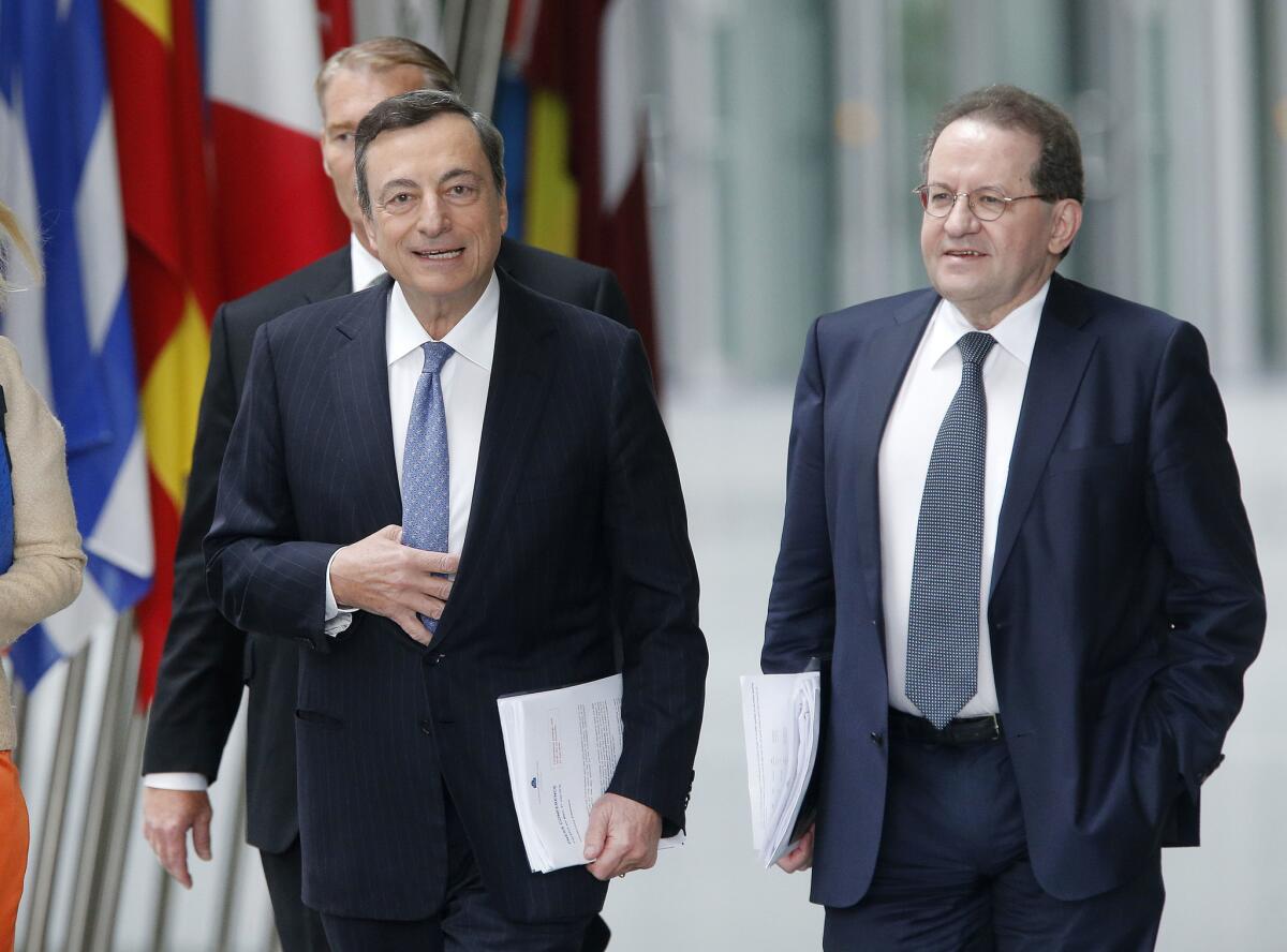 European Central Bank President Mario Draghi, left, heads Thursday to a news conference in Frankfurt, Germany. The bank left key interest rates at a historic low following Britain's decision to leave the European Union.