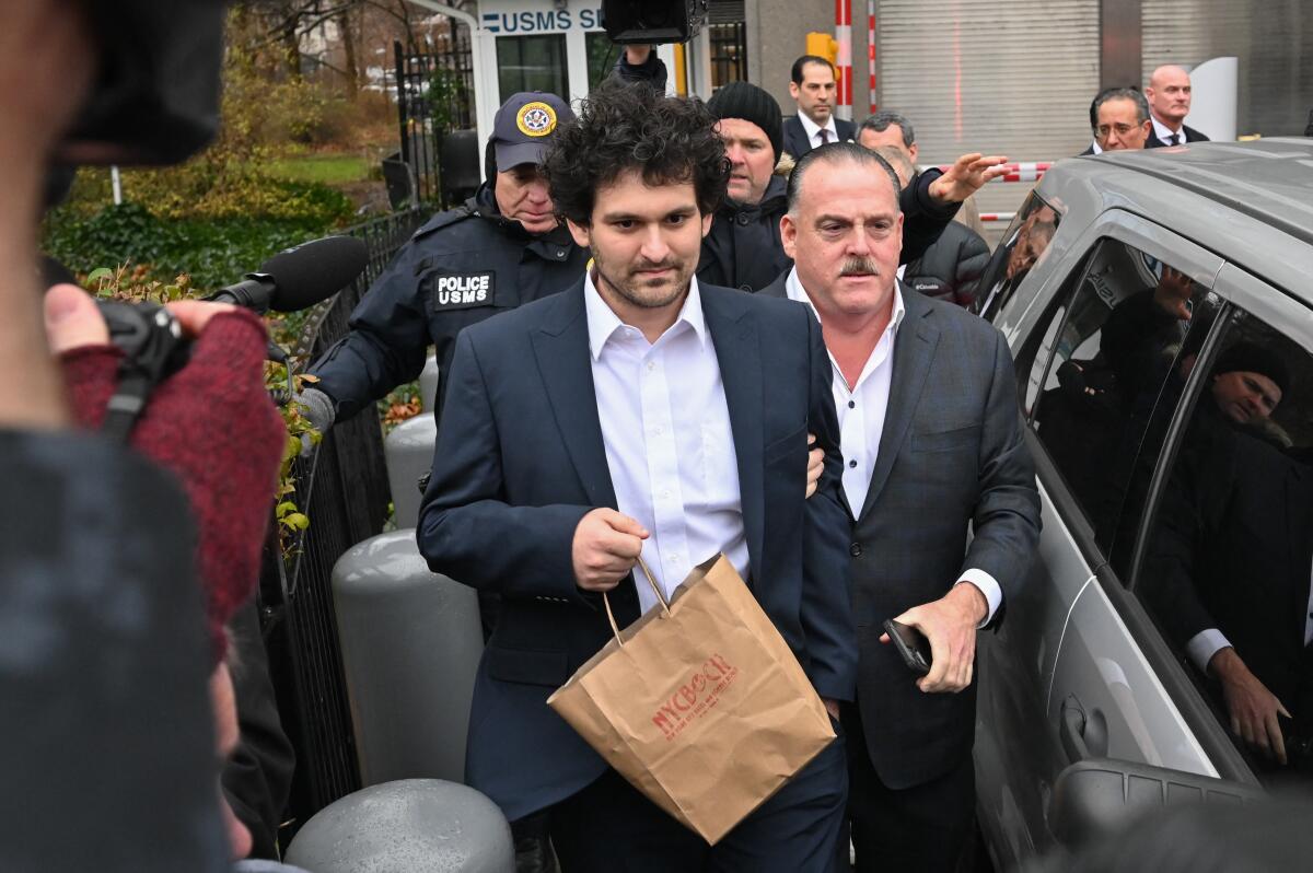 Sam Bankman-Fried leaves court with men following him.