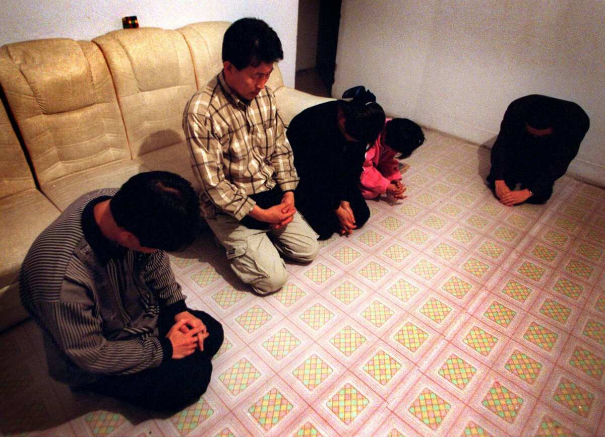 South Korean missionary Chun Ki Won, second from left, leads a group of North Koreans in prayer in a safe house in northeast China. Chun leads such refugees along an Asian underground railroad to South Korea. They risk death or torture if they are captured.