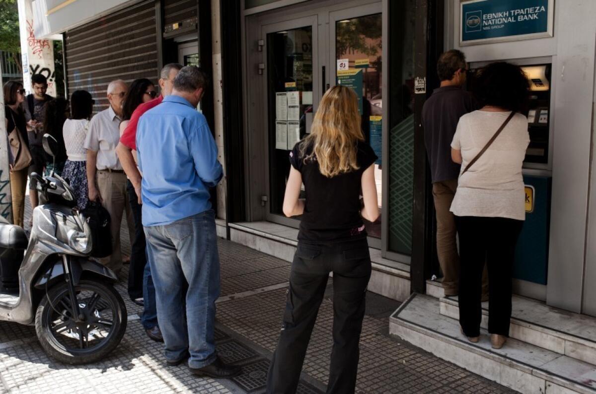 Un grupo de personas hacen fila en un cajero automático en Atenas. Los bancos sólo permiten a los griegos retirar un máximo de 60 euros diarios.