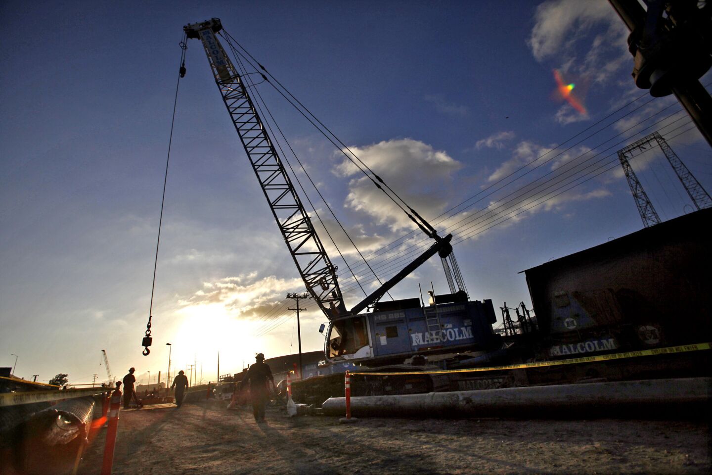 A giant crane swings a hook to pick up metal plating in preparation for constructing the new bridge.