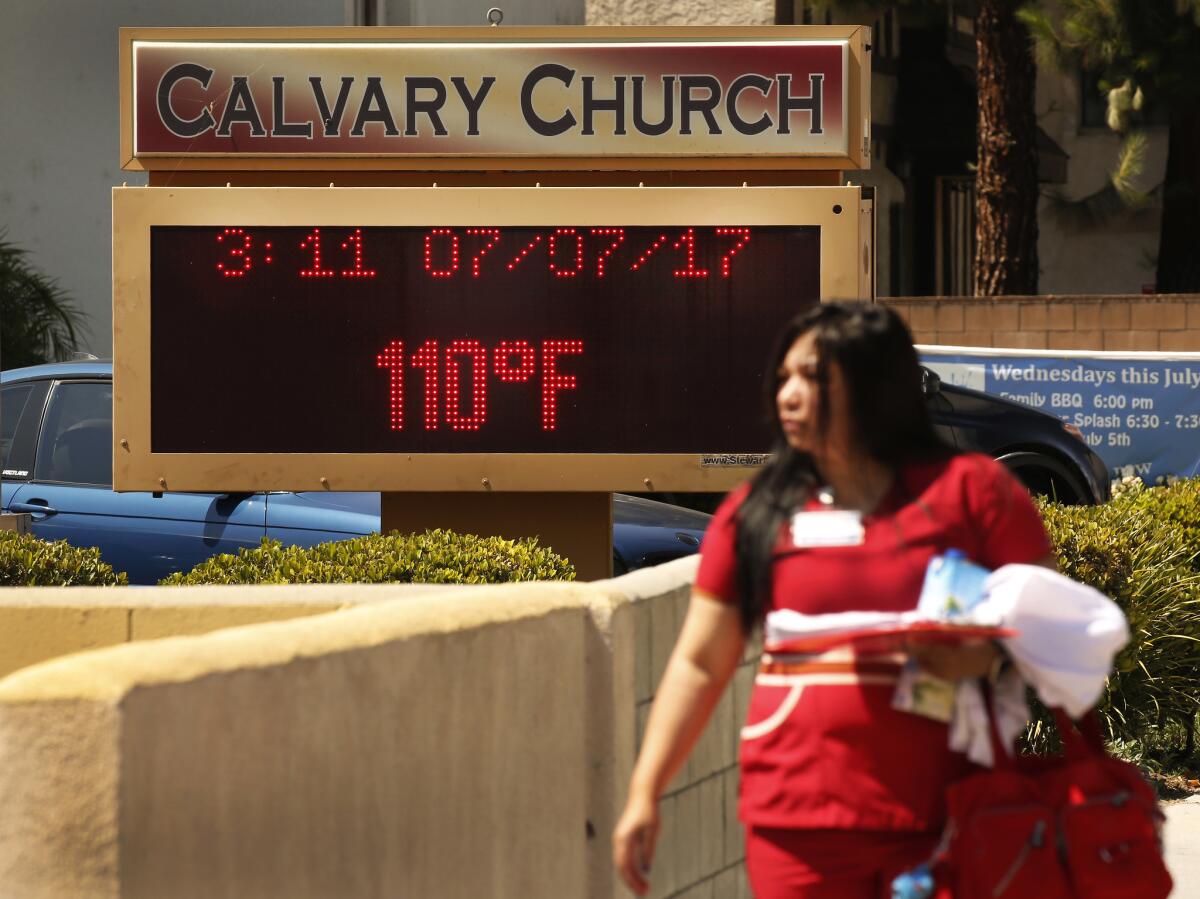 People brave record 110-degree temperatures Friday while walking to work in West Hills in the San Fernando Valley.